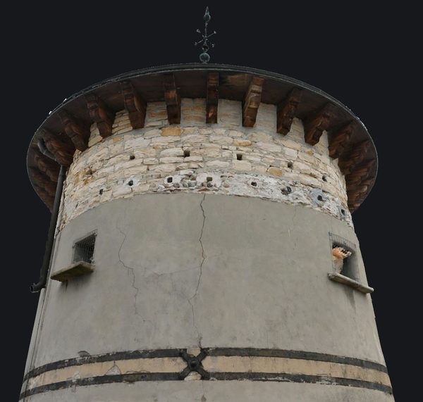 Le maillage texturé de la tour ronde de Vaux, vu de près&nbsp;: les
                       moellons, l'enduit fissuré et la charpente de l'avant-toit.